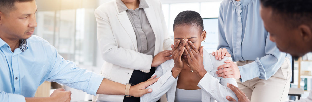 Femme qui pleure au travail et qui est soutenue par ses collègues