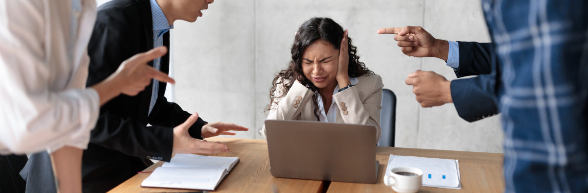 Femme qui se bouche les oreilles car elle est victime de l'agressivité d'autres personnes sur le lieu de travail